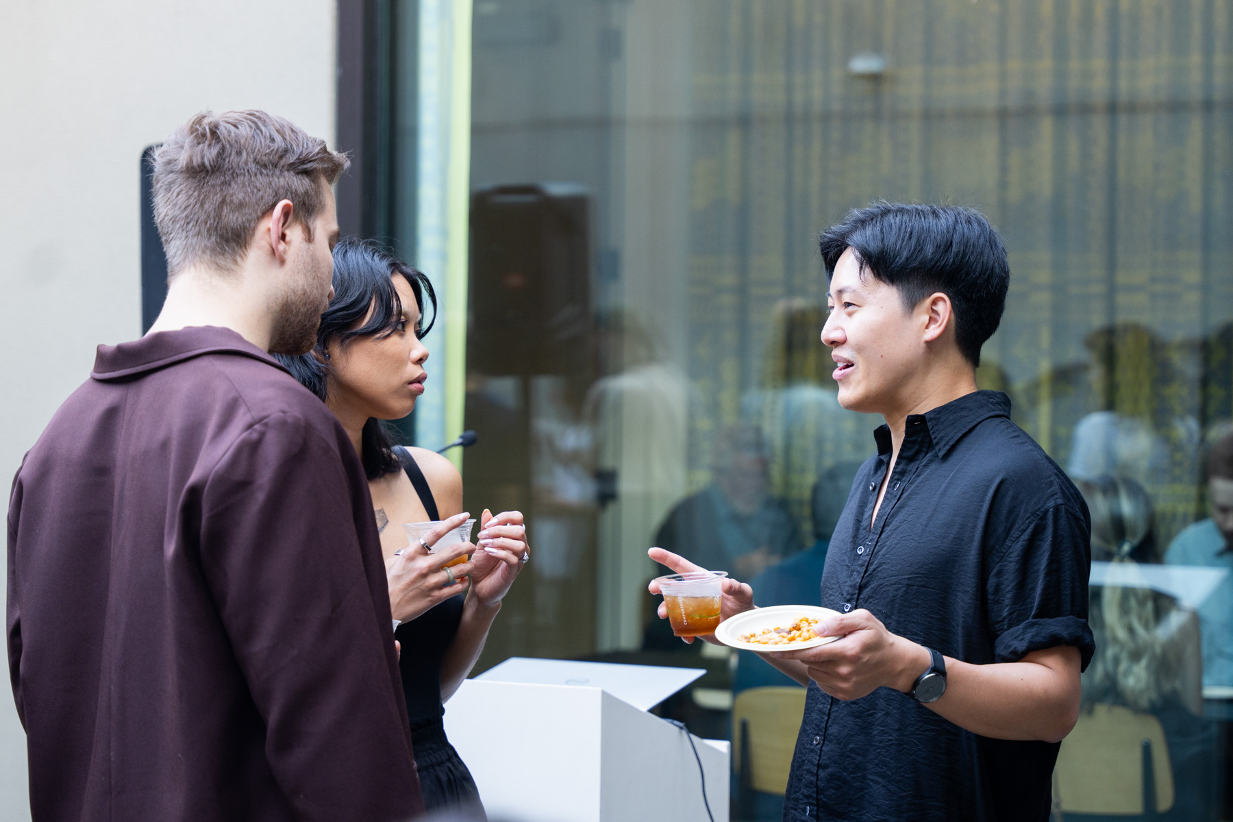 Three people chatting and drinking in the Frye Courtyard