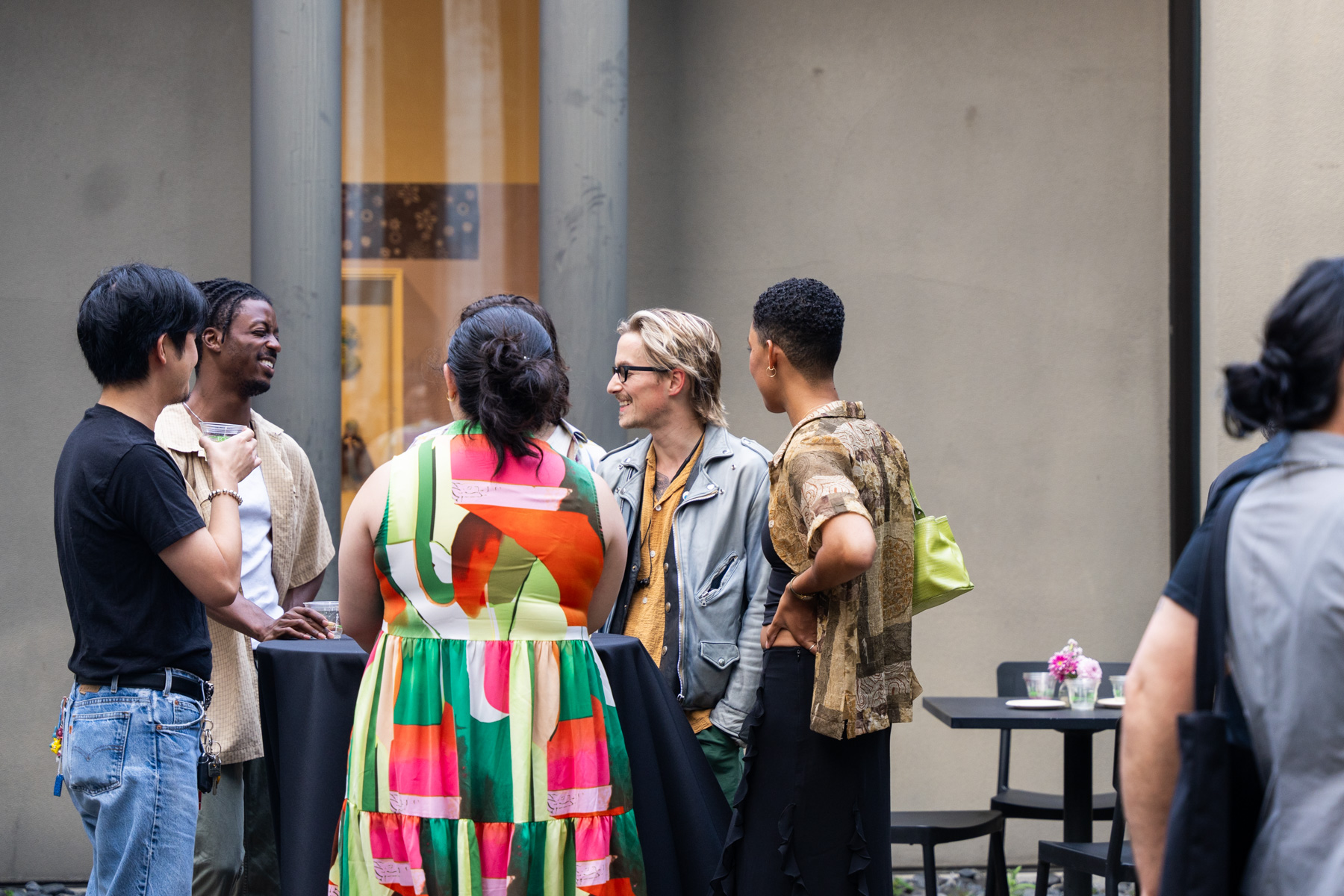 A group of people standing around a table and chatting in the Frye Courtyard