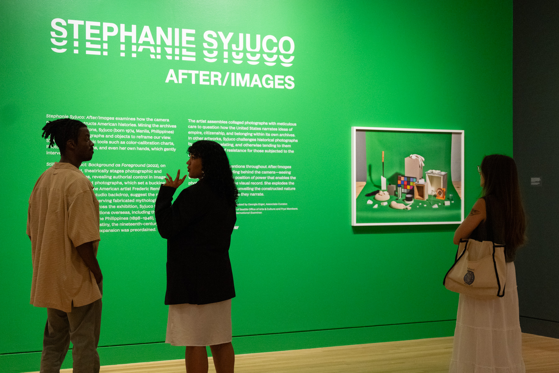 People looking at a green exhibition title wall 