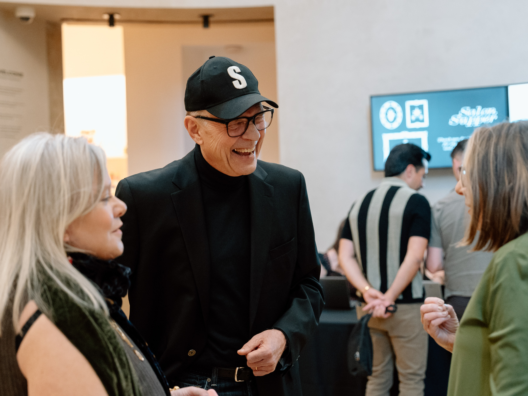 A small group of people smiling and greeting each other in an circular entryway space in a museum