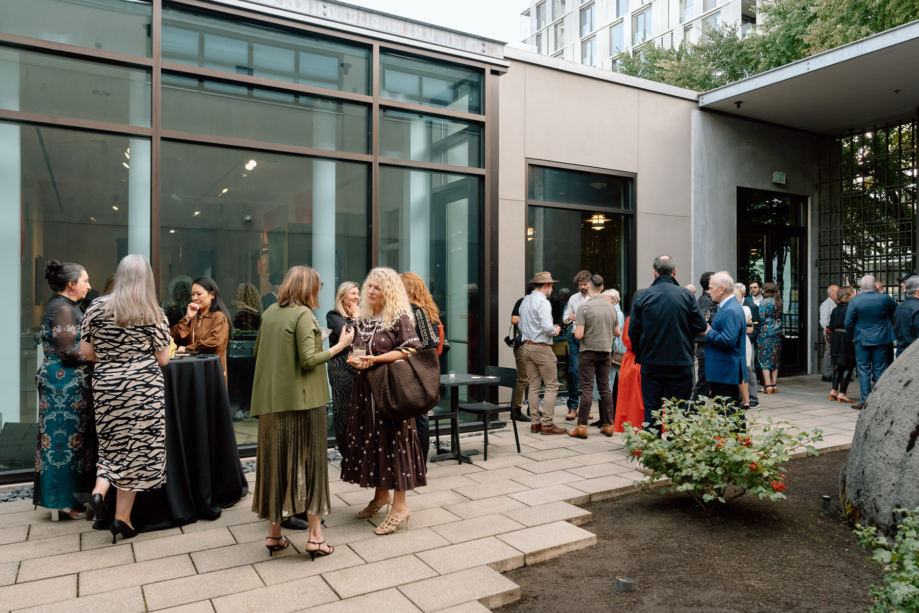 An outdoor courtyard in the evening with small groups of chatting people in cocktail party attire