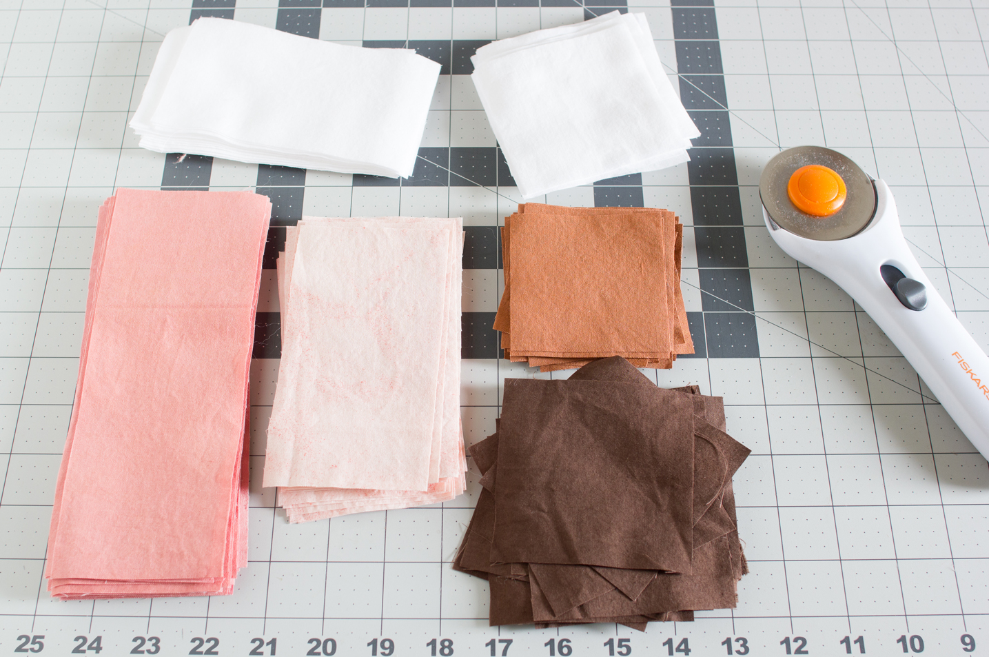 Photo of naturally dyed fabric in stacks on a cutting mat