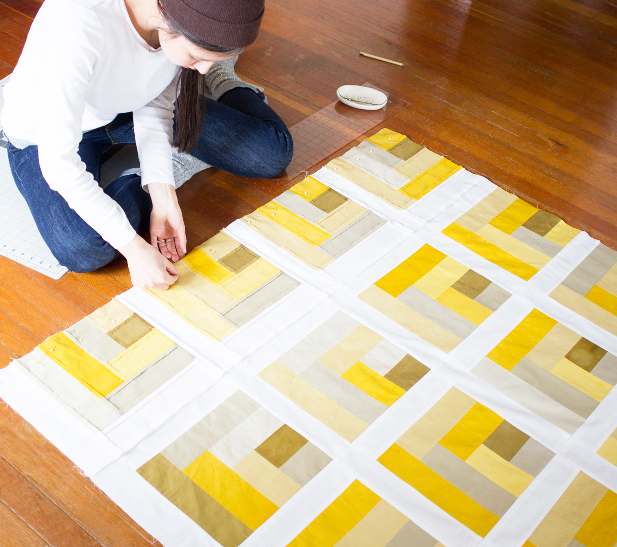 Photo of artist Naomi Parker sitting on the floor working on a quilt