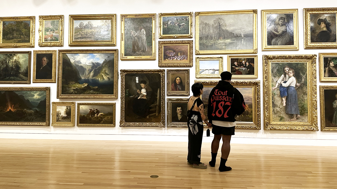 Photo of the Frye Salon with two people viewing the paintings