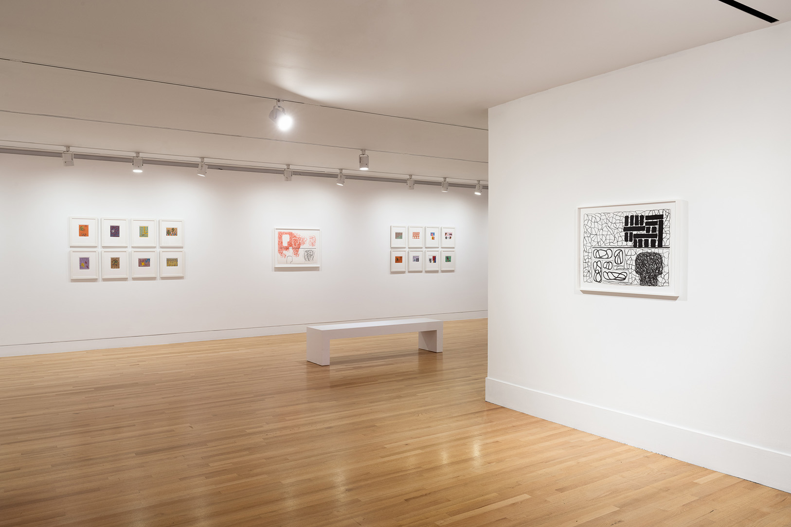 A gallery space with small, framed artworks on white walls