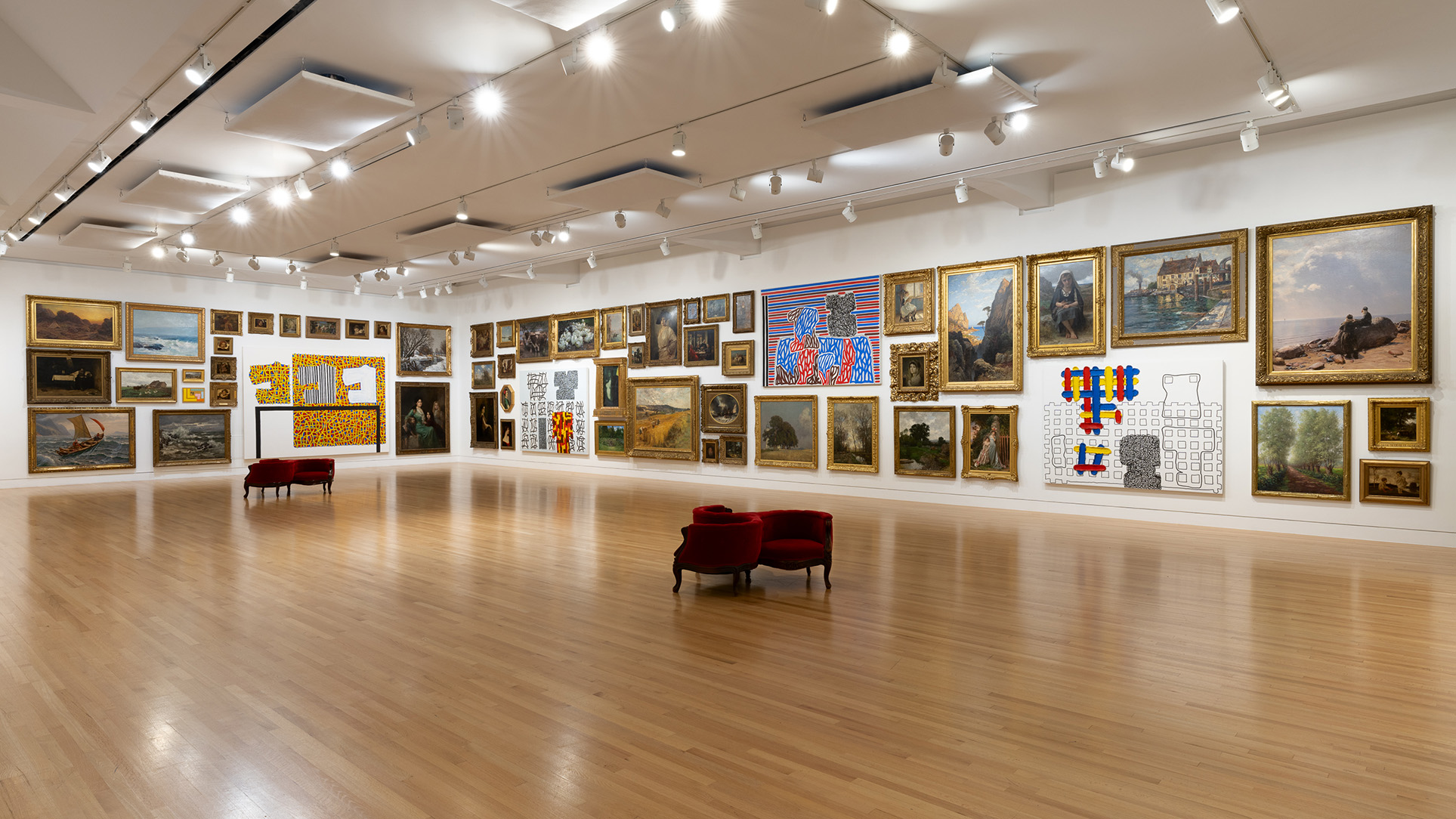 A large room with a mix of traditional and abstract paintings hung densly on the walls