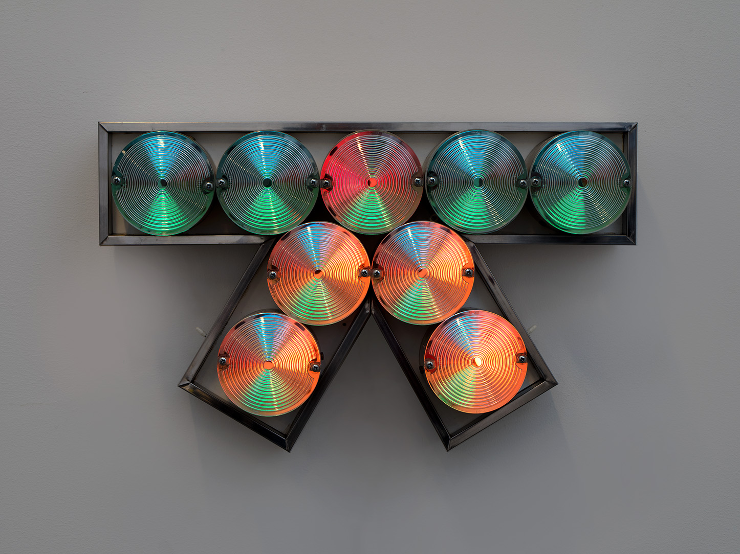 A light based artwork with large, circular bulbs in the shape of a 'k' turned 90 degrees clockwise