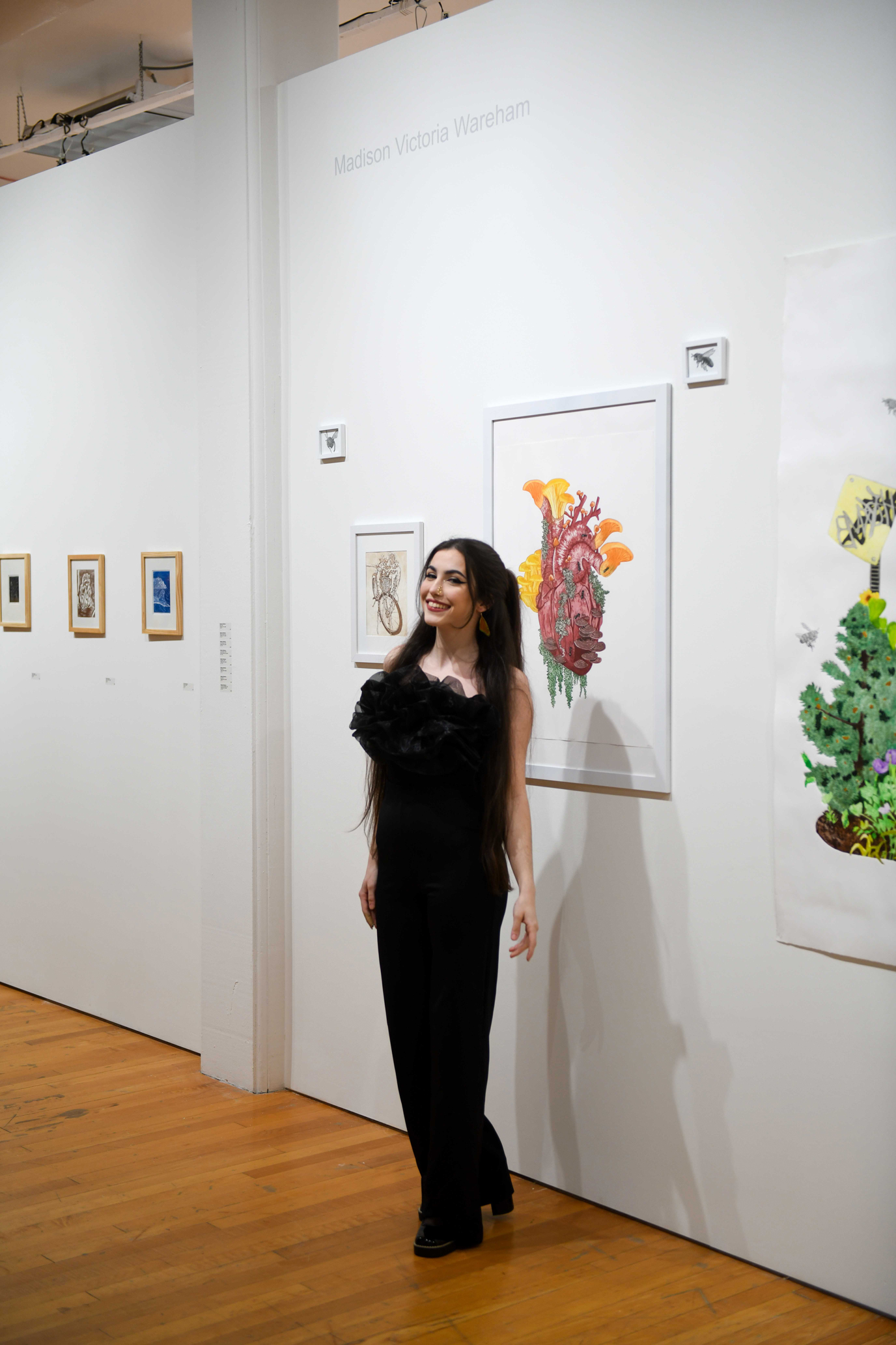 Photo of Maddi Wareham smiling in front of colorful prints of hers