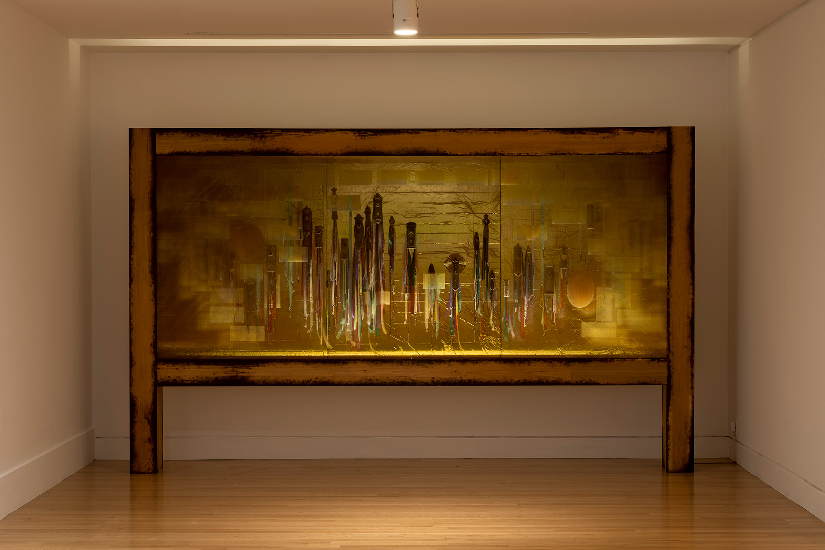 A large artwork installation with ribbons and other items disguised behind a semi-transparent screen