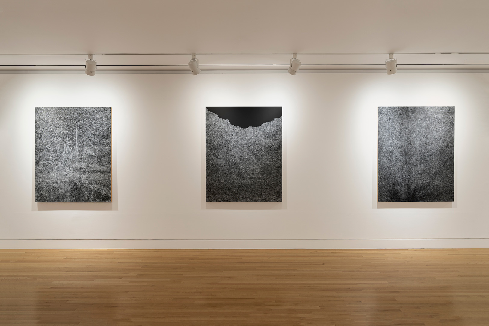 Three large, abstract black and white artworks on a wall