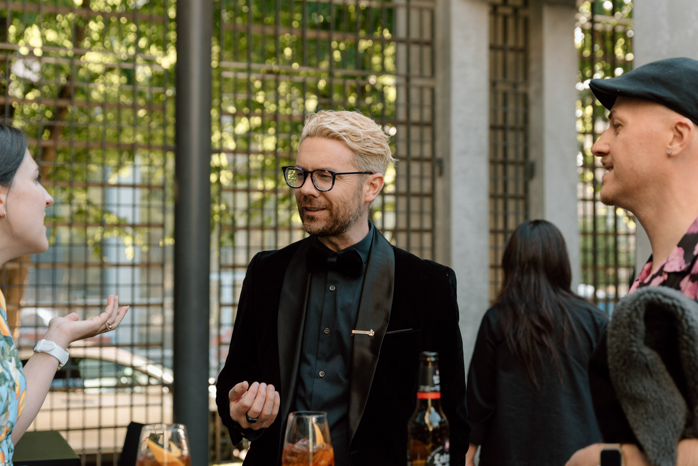 People standing and talking around a table in a sunny courtyard