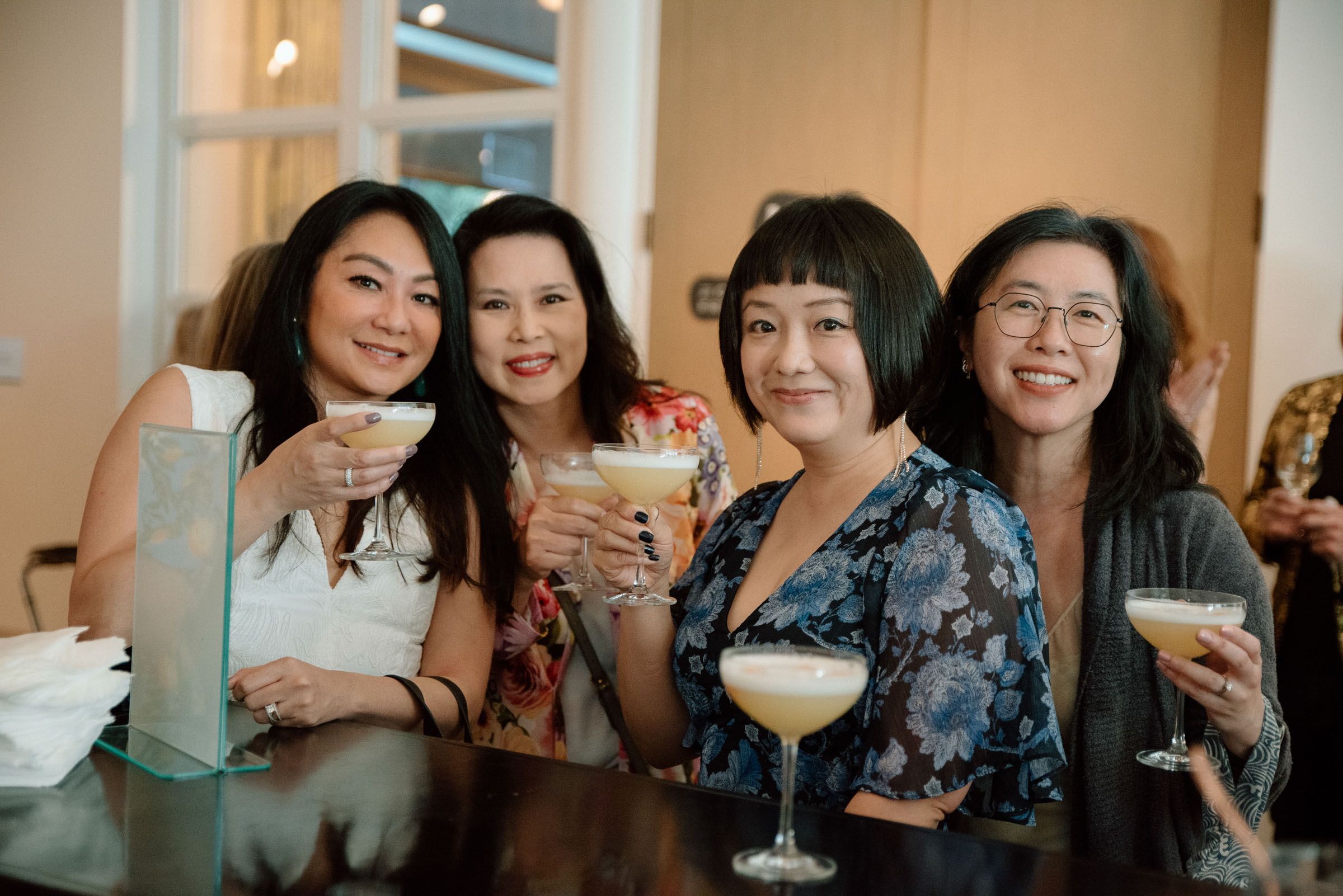 Four women smiling and holding drinks in cocktail glasses
