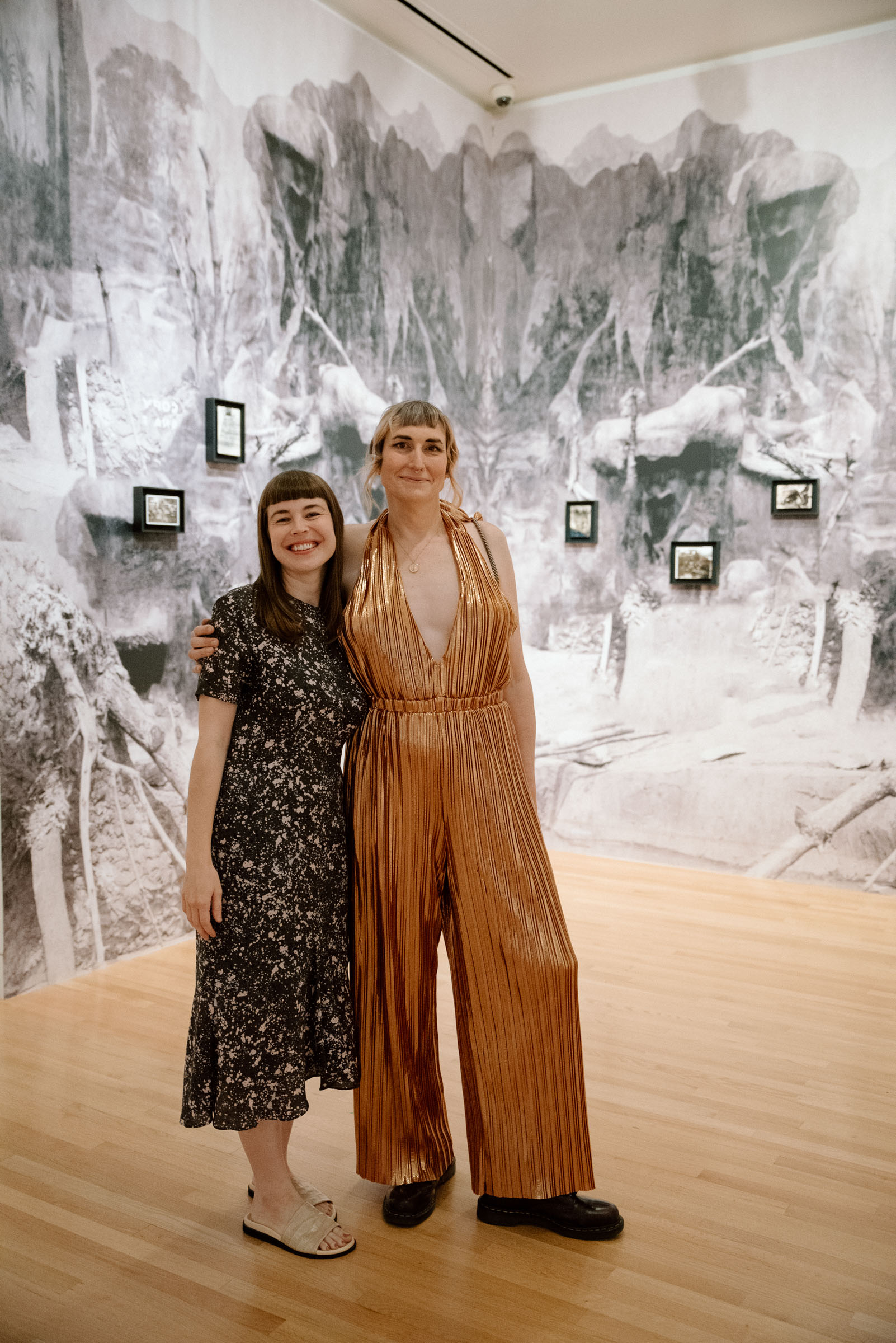 Two women standing and smiling in a room with art on the walls