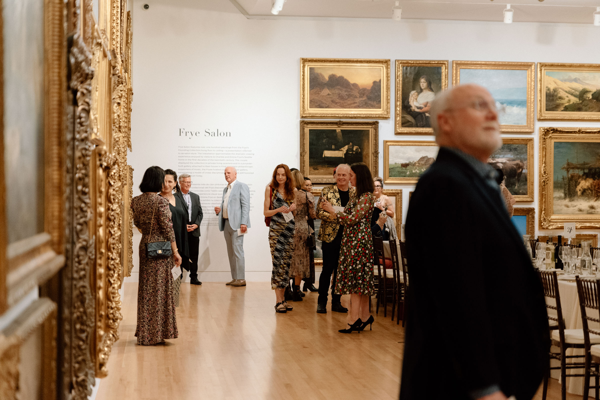 People entering a large room with walls covered in art and a long table laid out