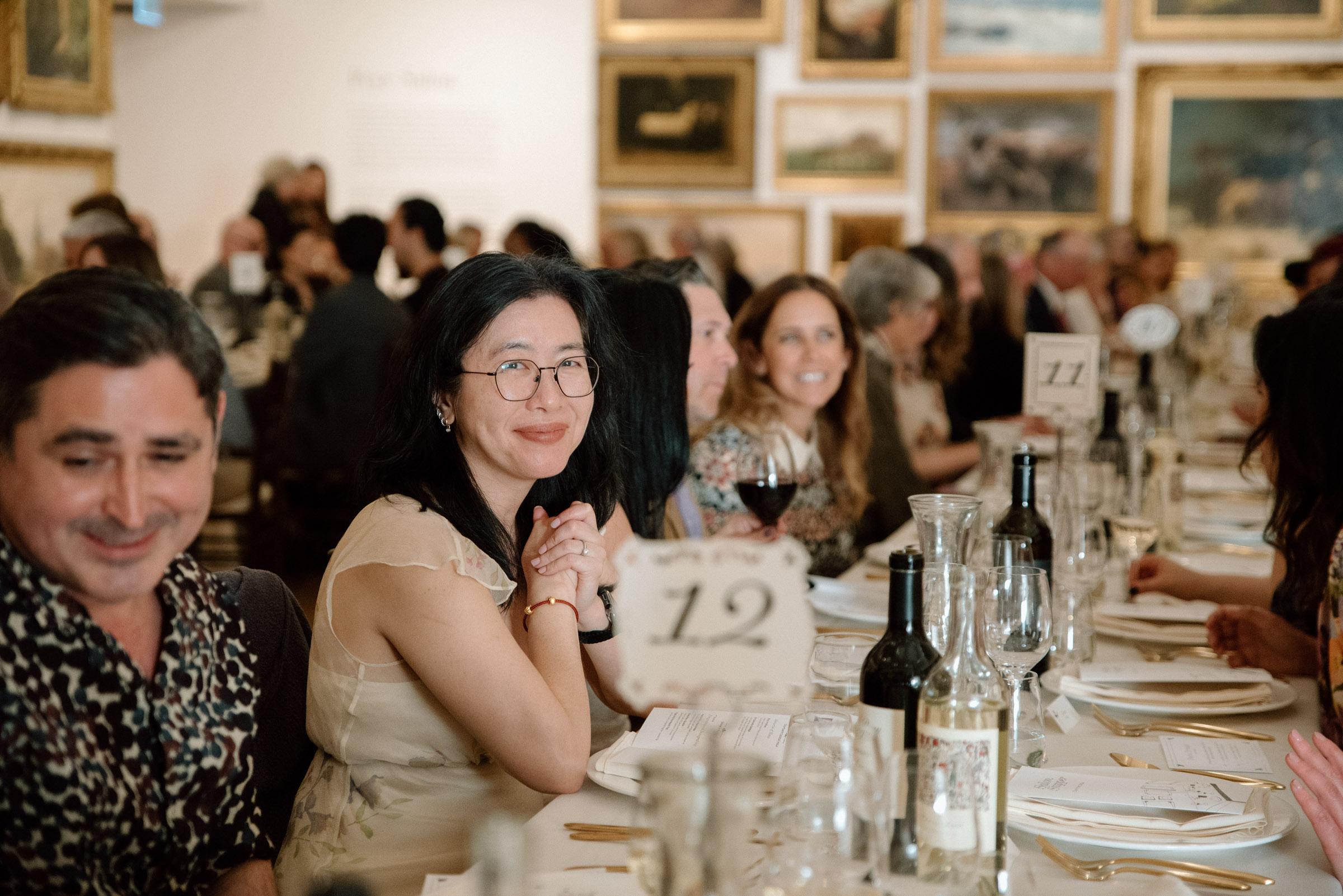 A person sitting at a long table and smiling with many people on either side
