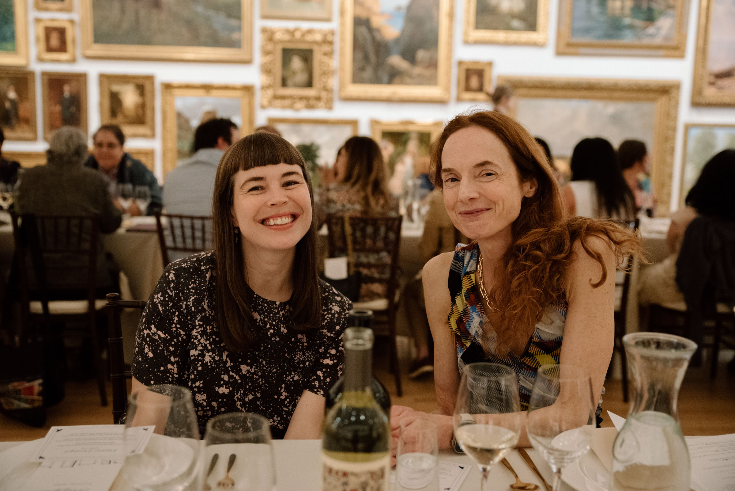 Two woman seated at a table smiling at the camera