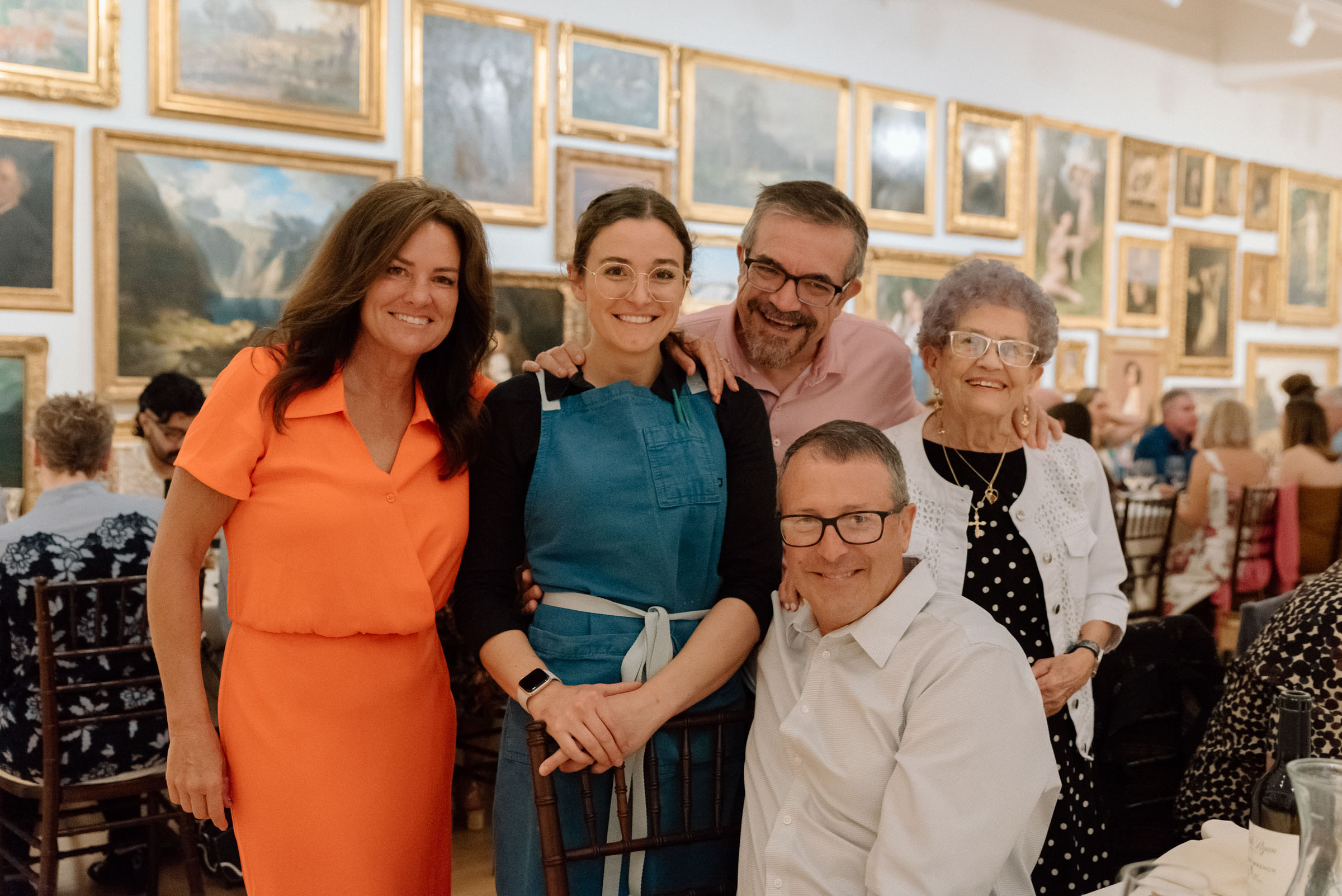 People standing in a group and smiling in a room filled with paintings