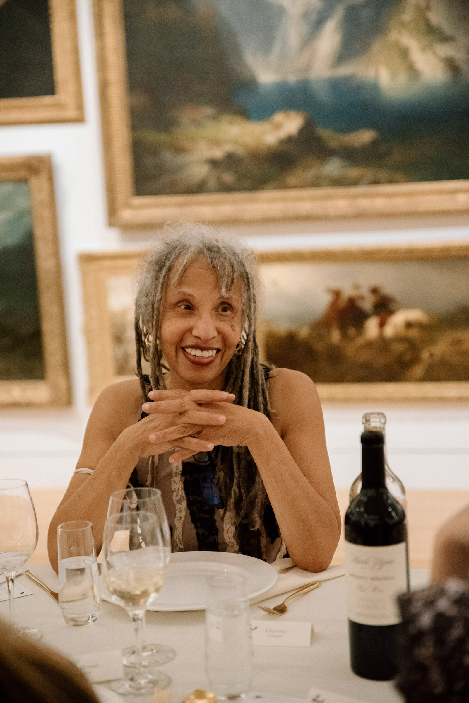A woman sitting at a well laid table in front of paintings