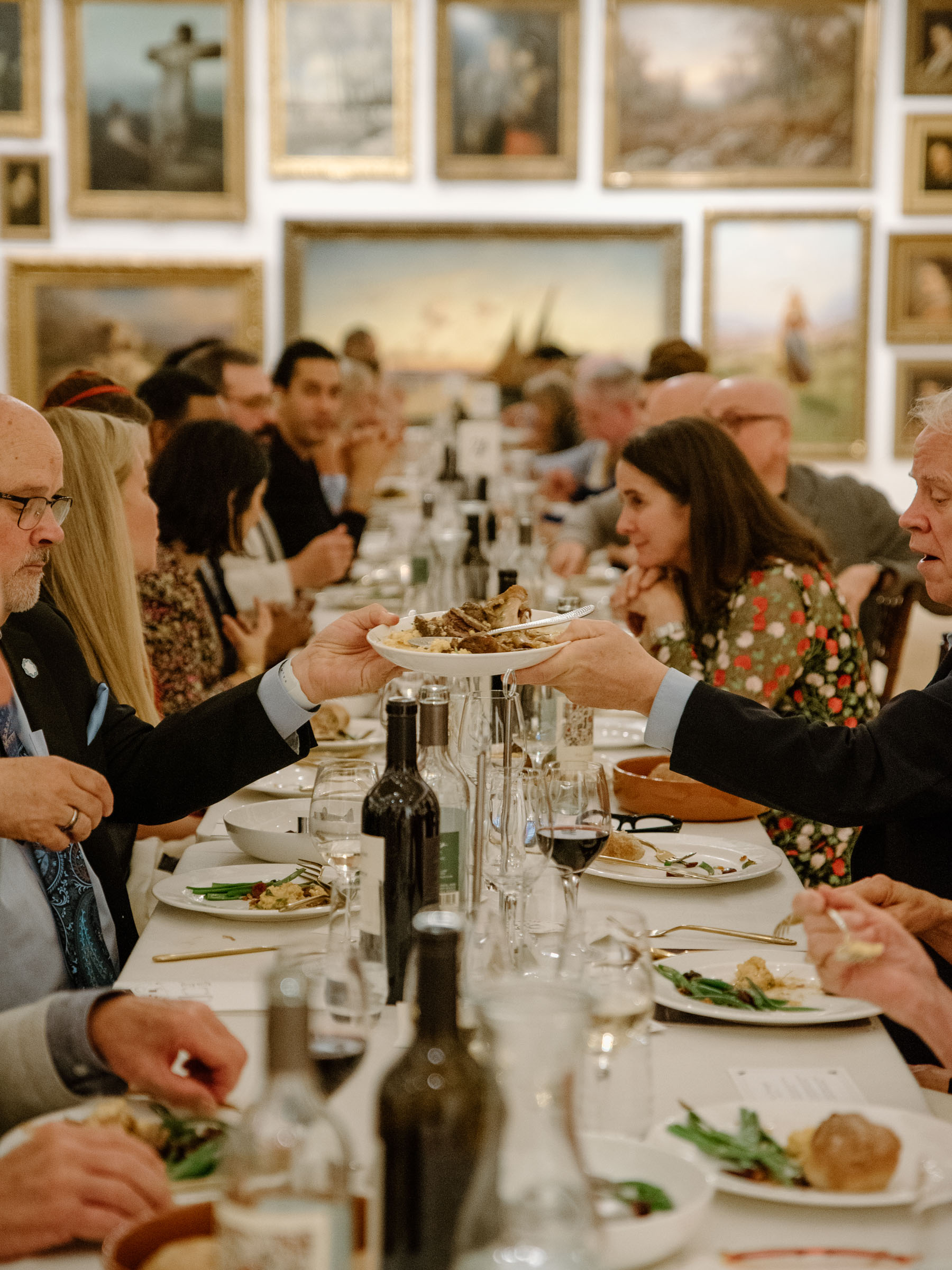 People sitting at a long table laid with wine and food
