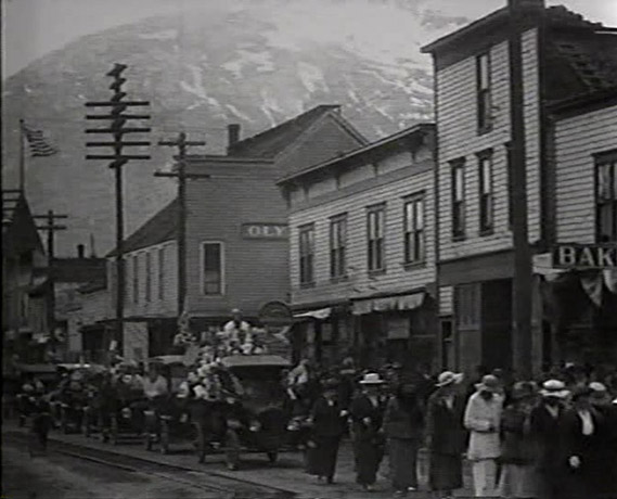 A still from a film of people in a street in a down in Alaska in the early 20th century