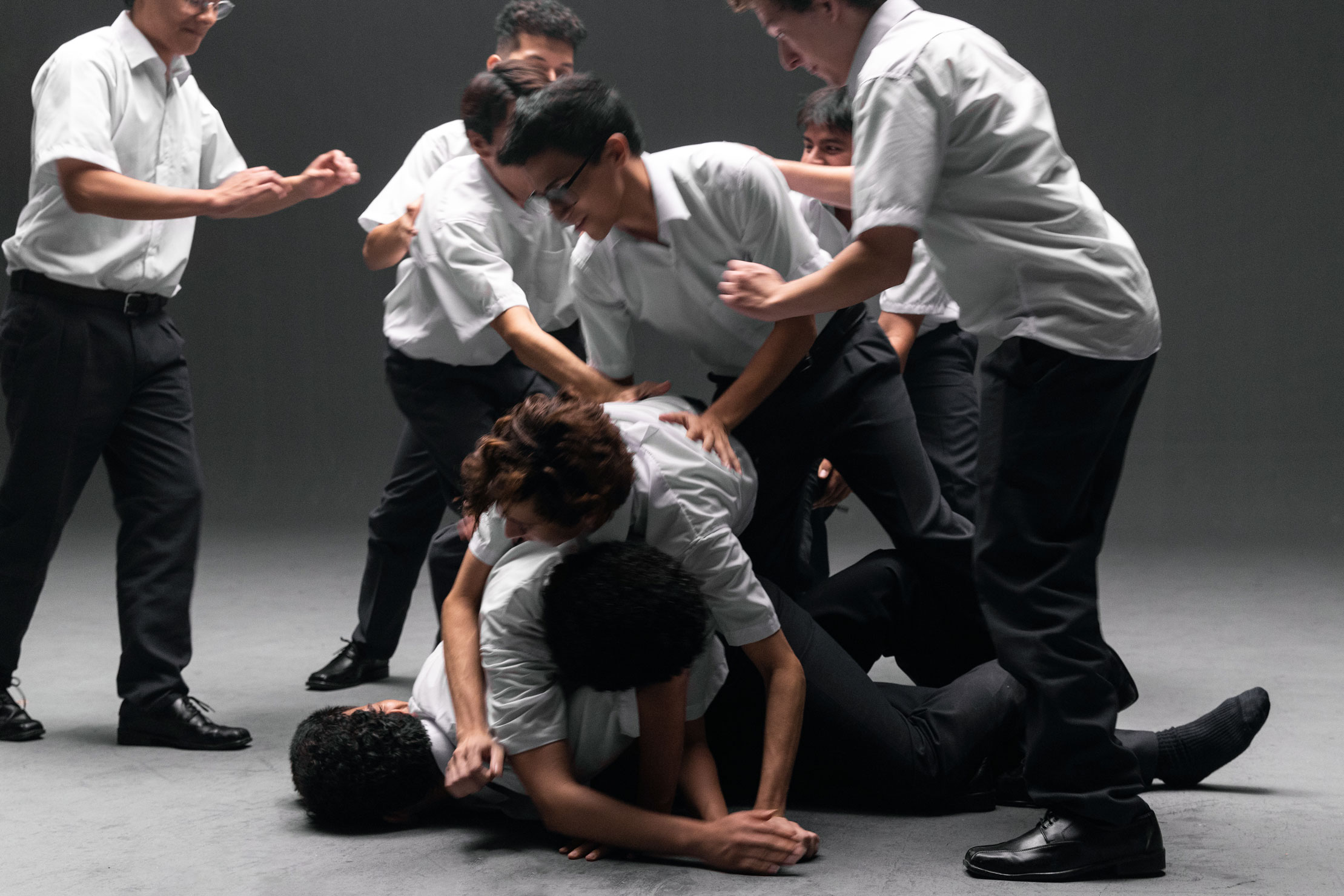 Video still of school boys wrestling, wearing white shirts and dark pants