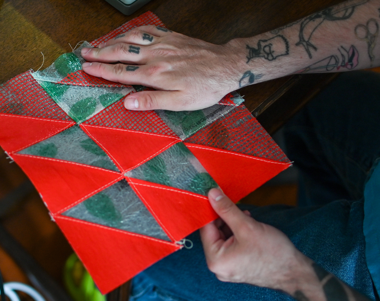 Hands holding a quilt square with red and green triangles