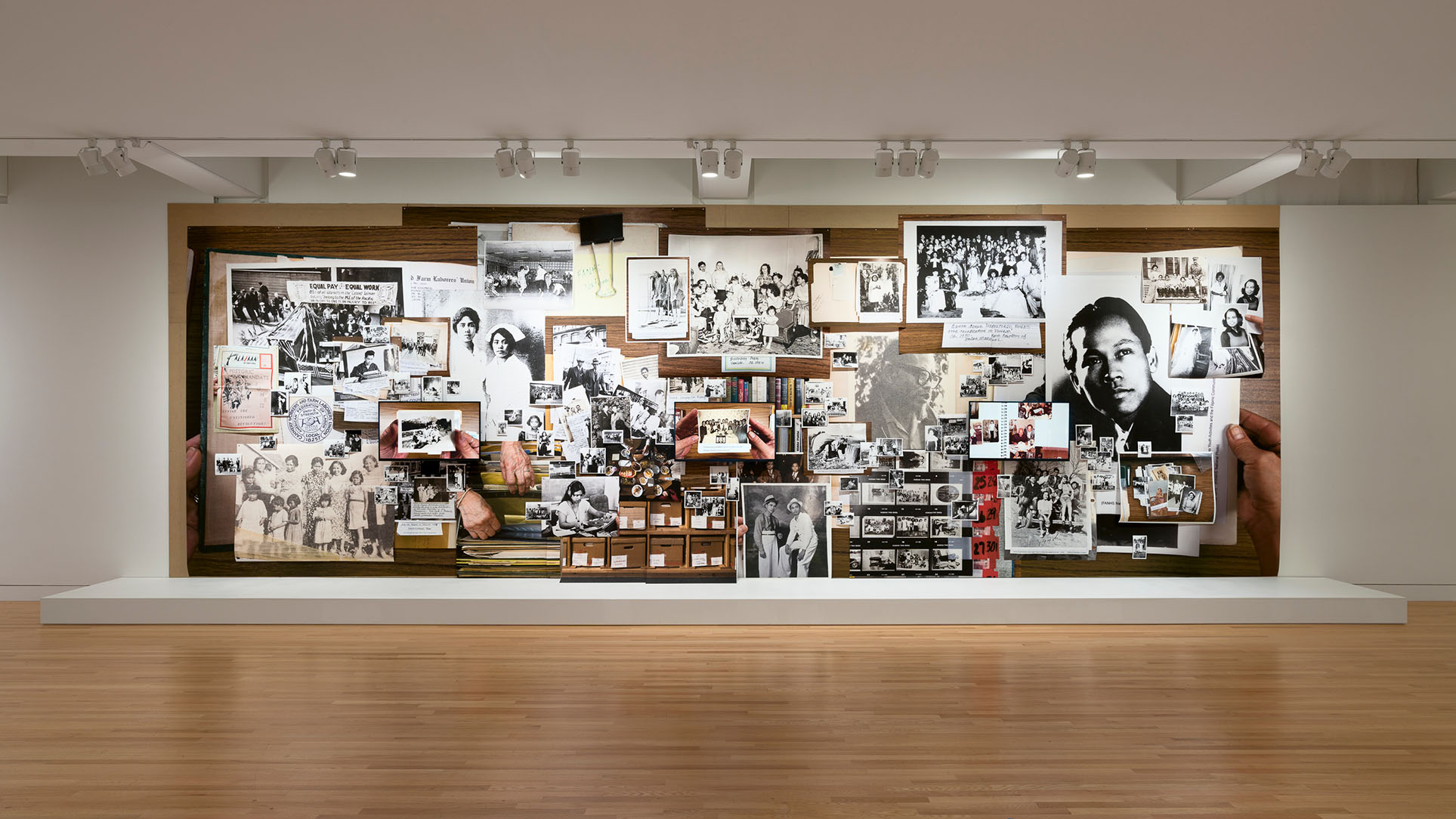A photo of a collage of images, mostly black and white, forming a single large installation on a wall