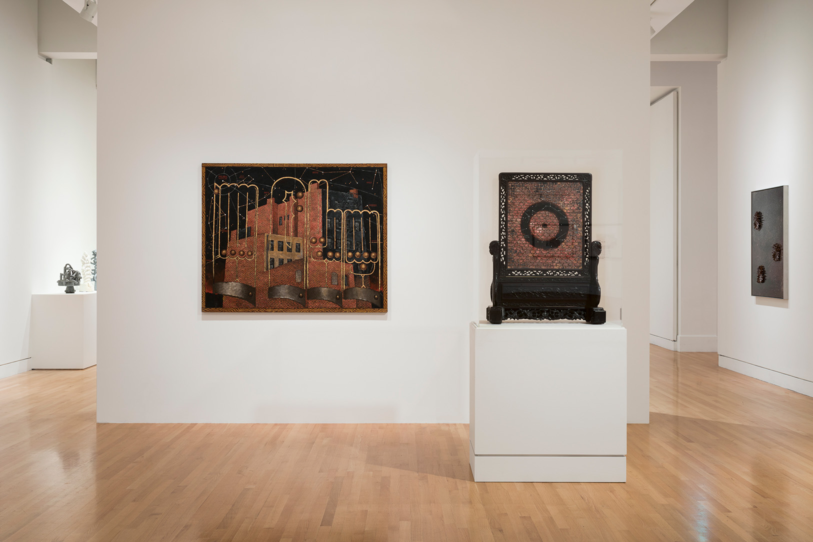 Photograph of paintings hanging on a wall and presented on a pedestal in a museum gallery