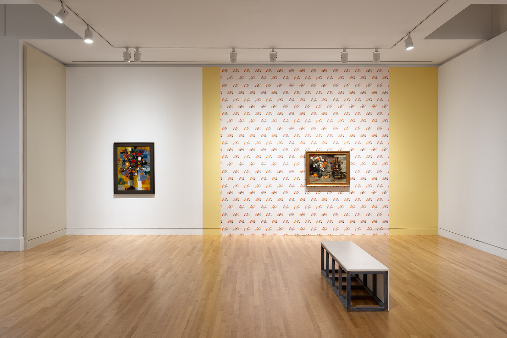 A large gallery space hung with a few still life paintings of flowers and large wall sections covered in colorful wallpapers