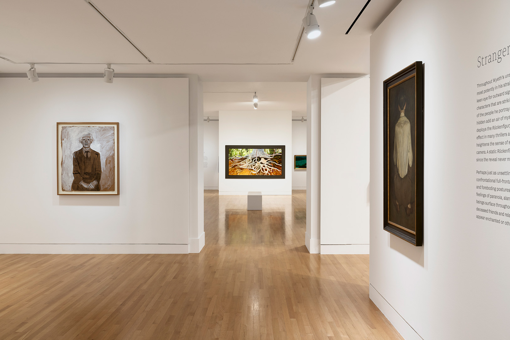 A view of a gallery space with paintings on the walls, including one of Andy Warhol