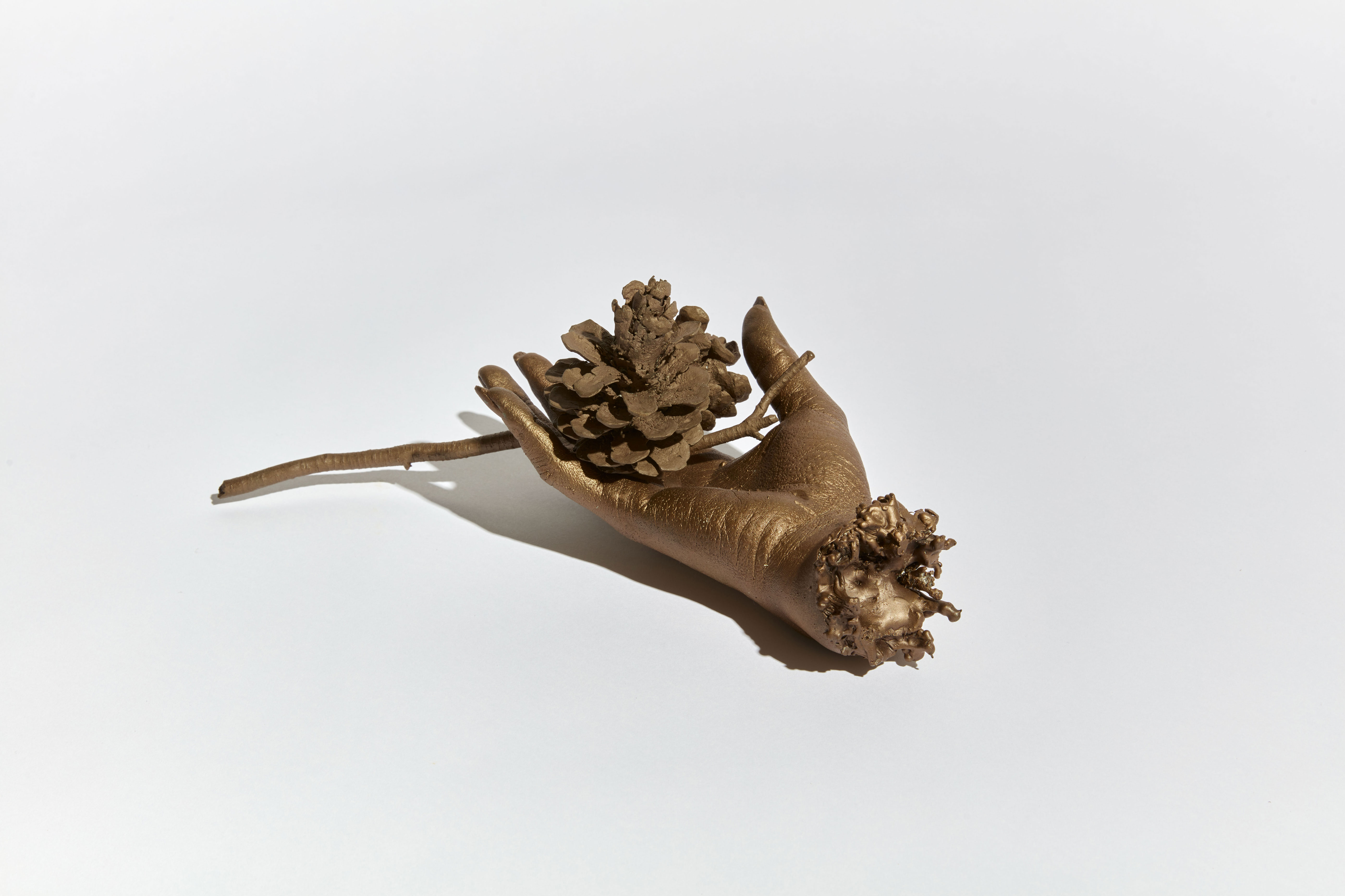 Cast bronze hand holding a pinecone