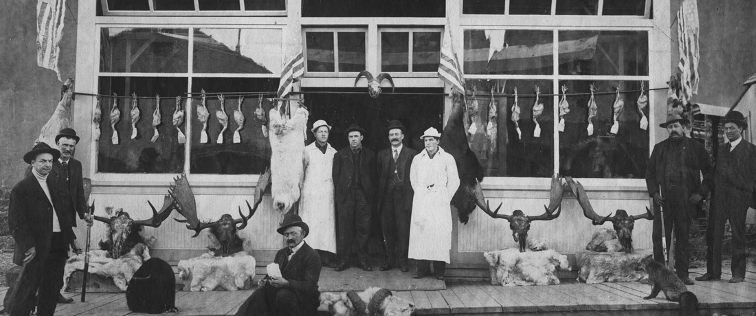 People standing in front of a storefront in Alaska in the early 20th century