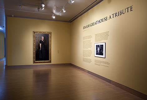 Installation view of an exhibition with a painting on a wall and exhibition text to the right