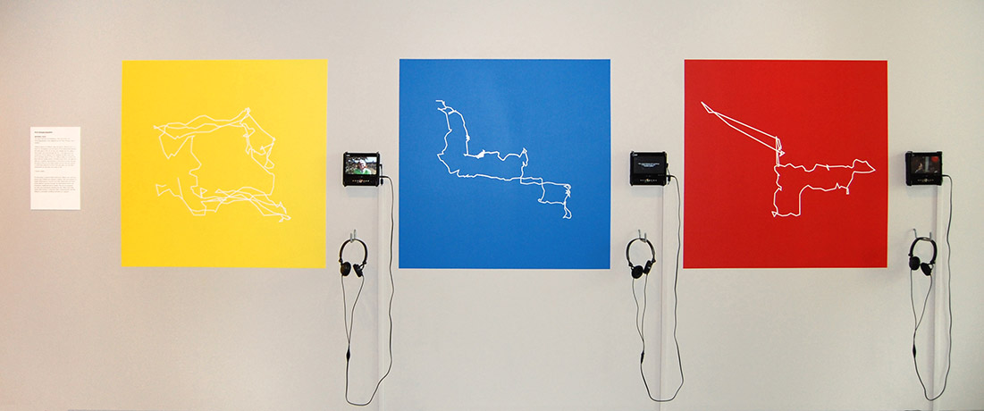 Outlines of geographic areas printed on sheets on a wall next to media players and headphones