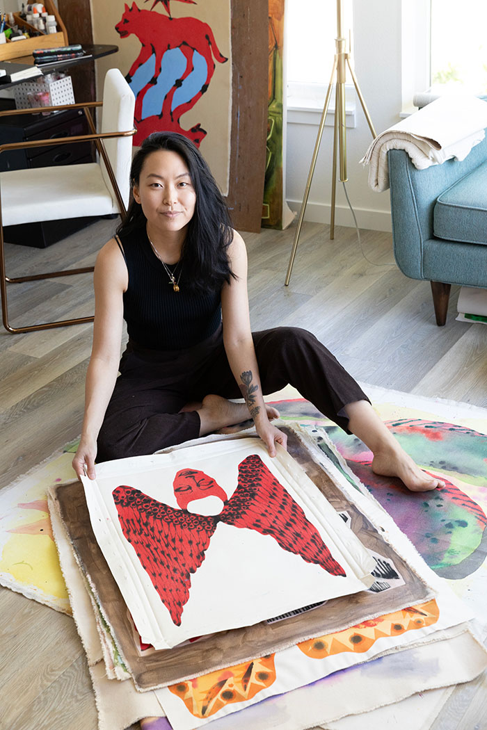 A person sitting on the floor behind a stack of artwork