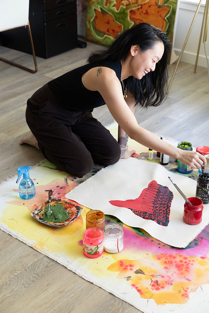 A person smiling and working on an artwork on the ground