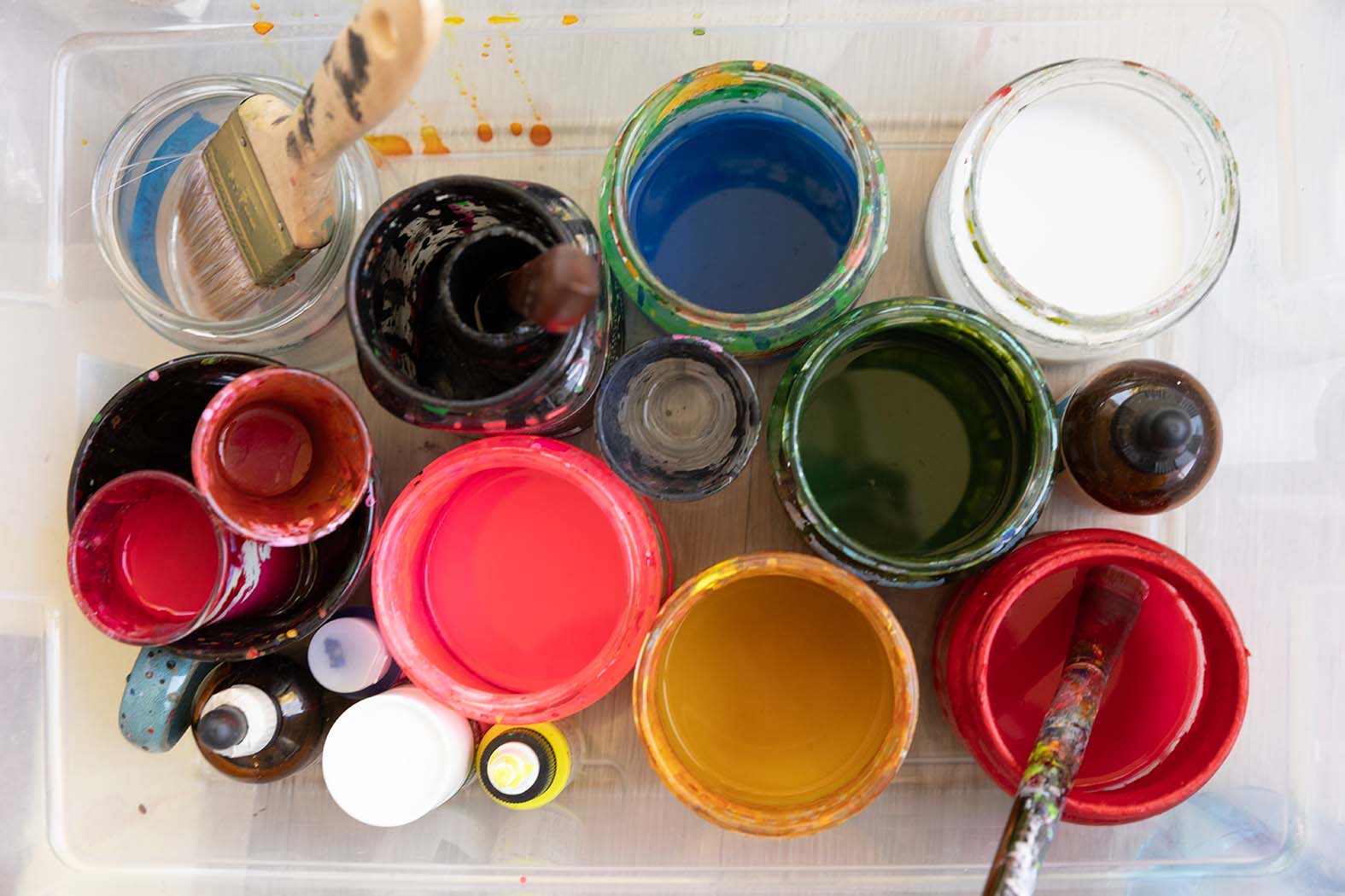 Cups full of painting and other art supplies photographed from above