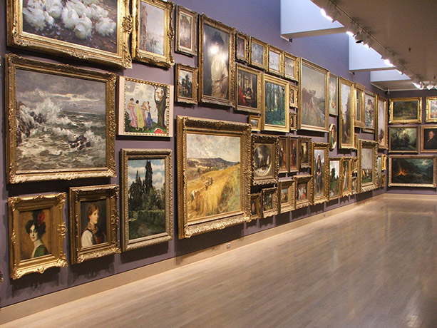 A museum wall covered in paintings
