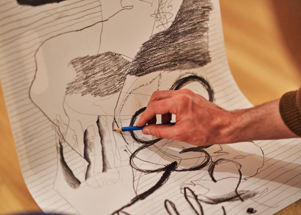A close up view of a person drawing abstract shapes in charcol