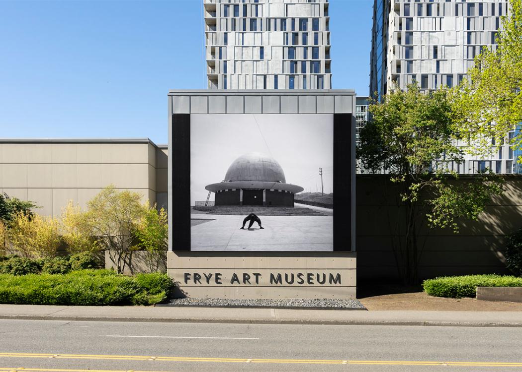 A large black and white photographic installed on the exterior of a building above text reading 'Frye Art Museum'