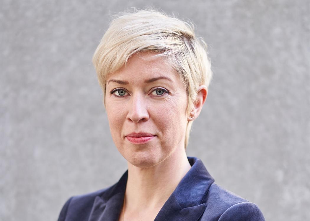 Professional headshot photograph of a woman with short, blonde hair
