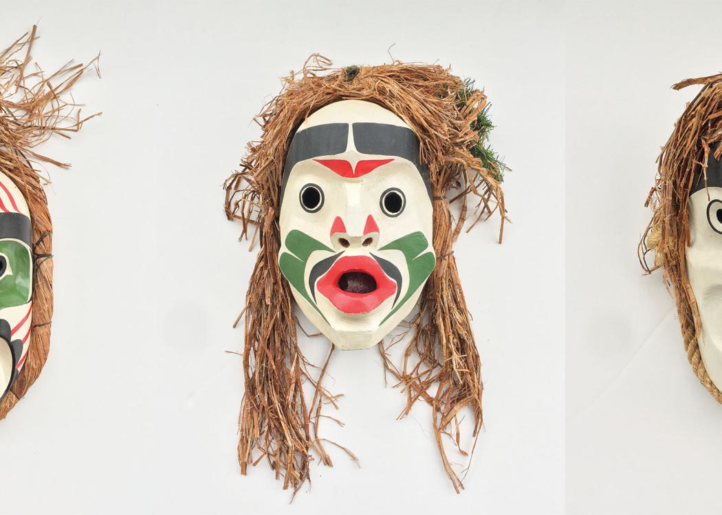 A series of three wooden masks painted white, green, black, and red with bark hair