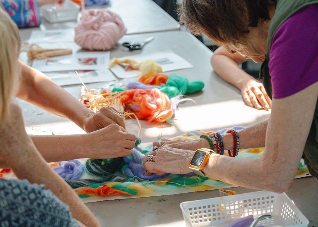 Peoples' hands reaching towards arts and crafts materials on a table