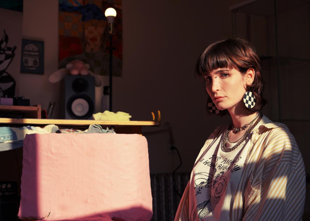 Photo of a woman with short brown hair with bangs and wearing checkerboard earrings