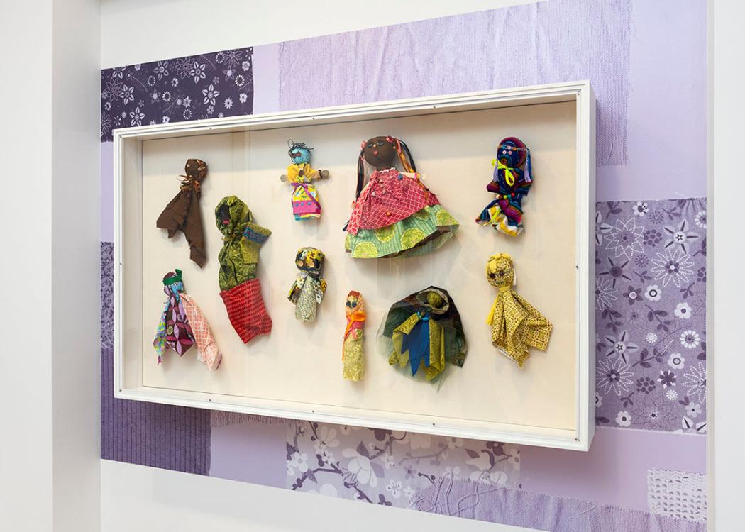 Dolls made of crafting materials in a glass case