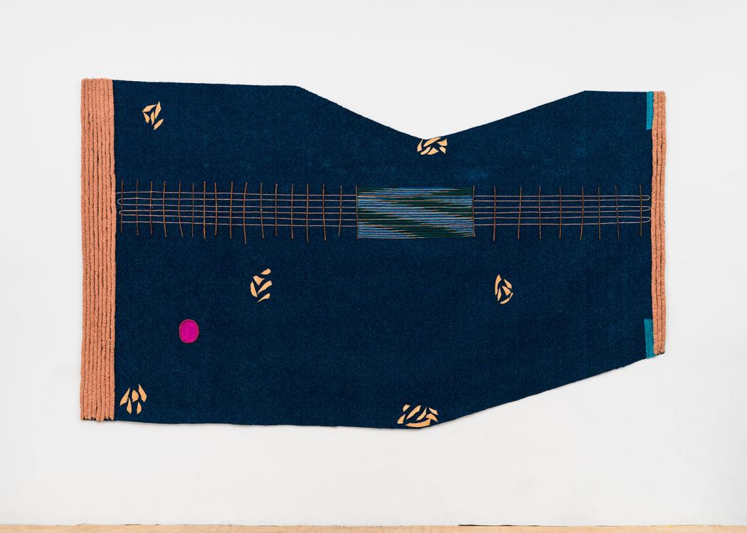 A dark blue textile artwork hanging on a white wall