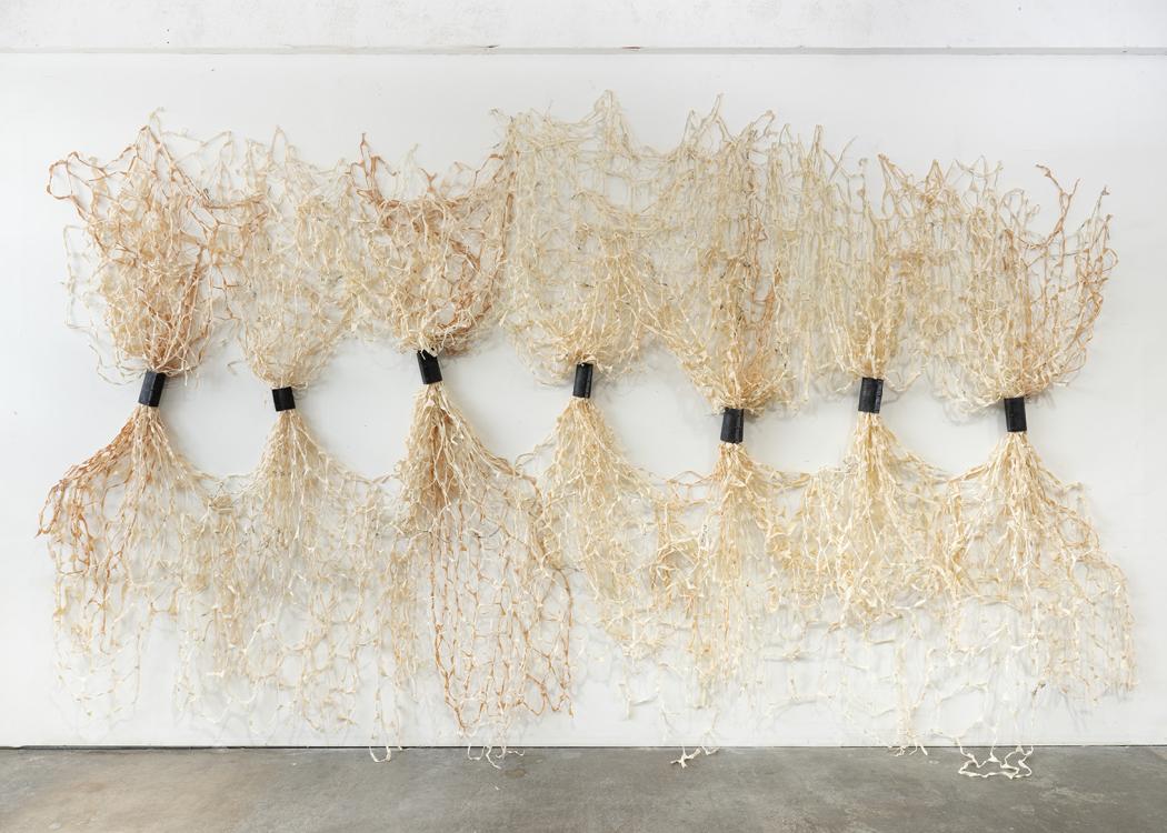 A large artwork consisting of bound, vertical sheaths of fabric
