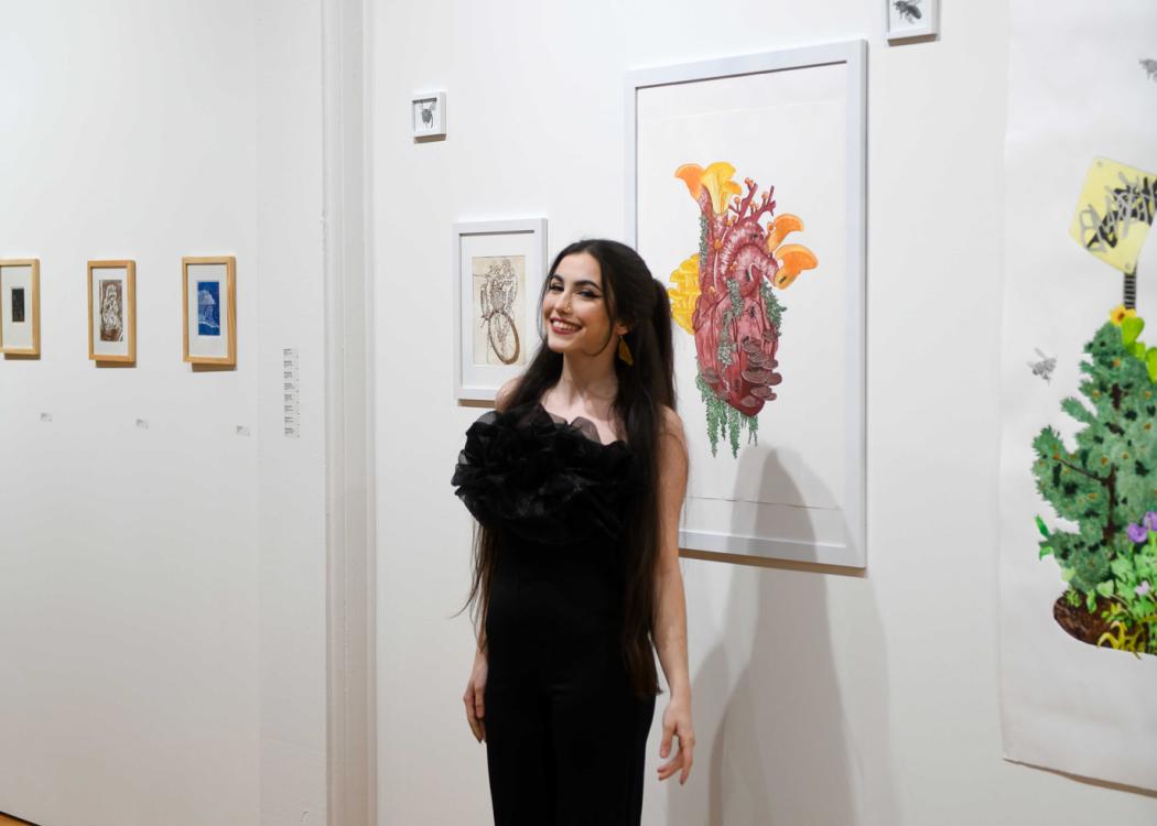 Photo of Maddi Wareham smiling in front of colorful prints of hers