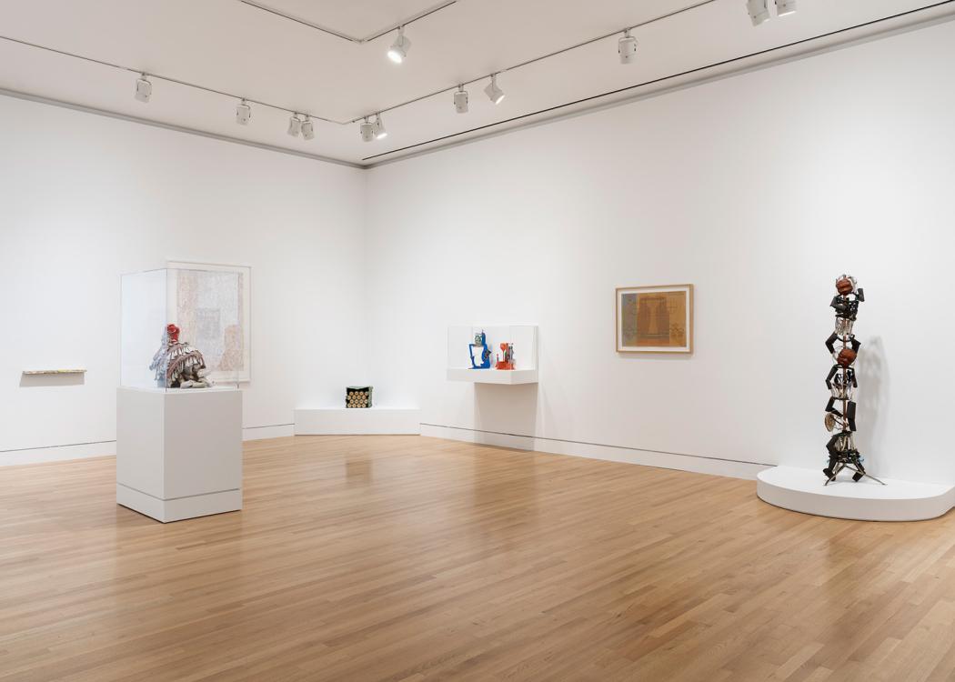 A view towards a corner of a gallery space with a variety of artworks