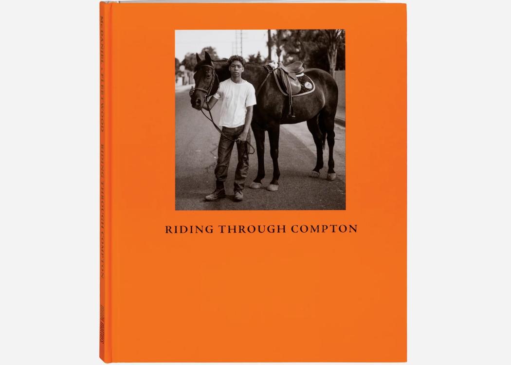 A book with an orange cover and a photo of a young black person standing with a horse with the words "Riding Through Compton" underneath